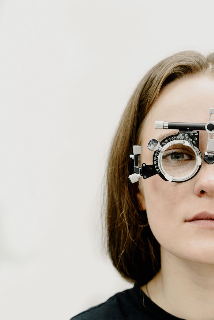 Crop female patient checking vision in metal rim with lens for examining visual impairments