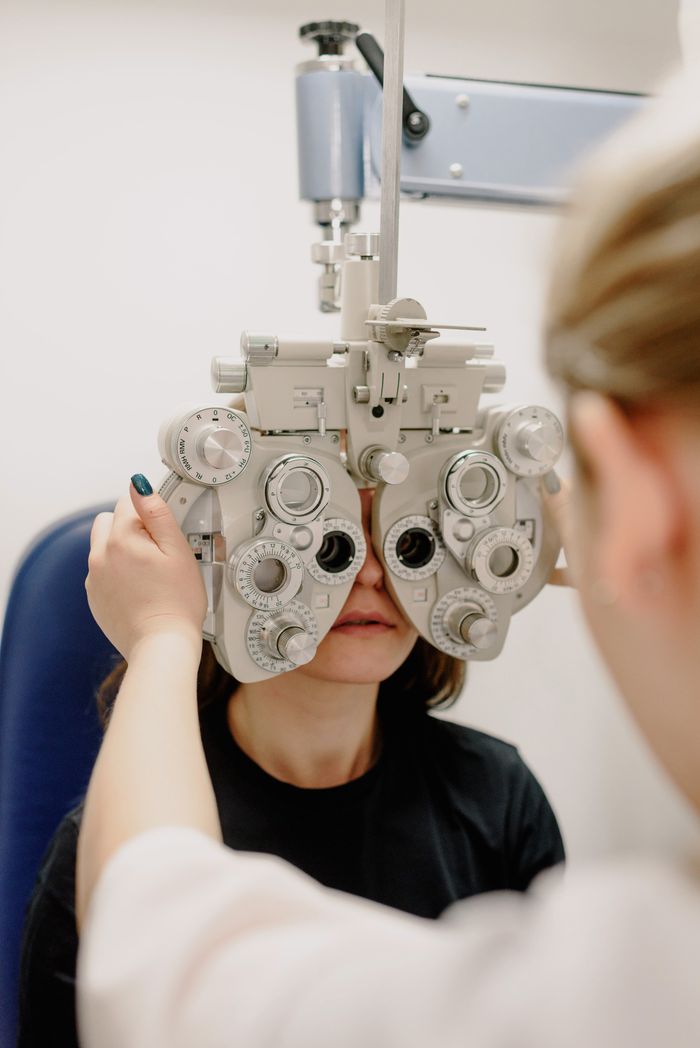 Unrecognizable female ophthalmologist adjusting medical equipment while doing vision check up of patient in contemporary clinic during work