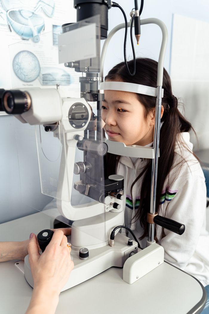 A teenage girl at an eye clinic examining her vision with optical equipment.